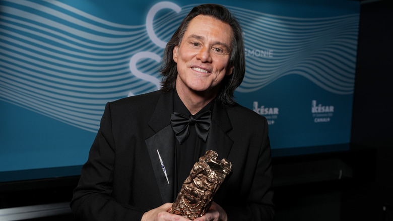 Jim Carrey holding his Cesar Award and smiling