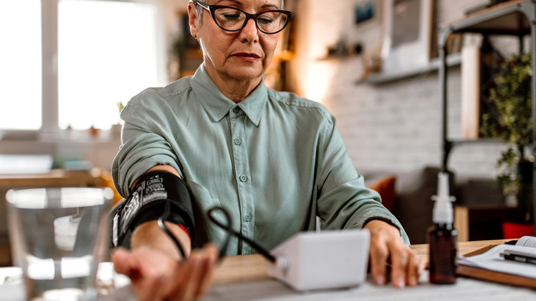 woman taking her blood pressure at kitchen table