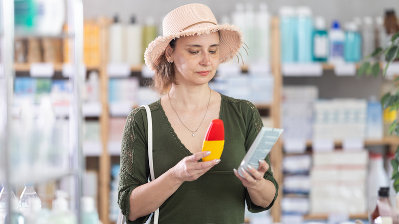 woman reading sunscreen ingredients in store