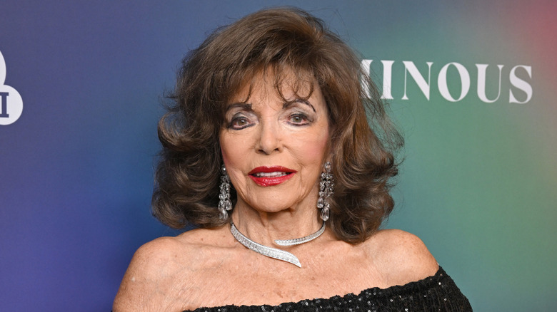 Joan Collins posing in a black dress