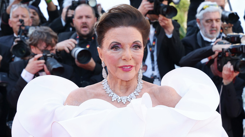 Joan Collins posing in a white dress