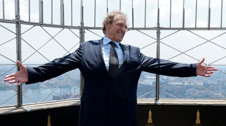 John Goodman outdoors with arms outstretched