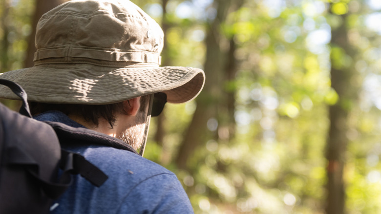 back of man wearing hat and protective gear in forest