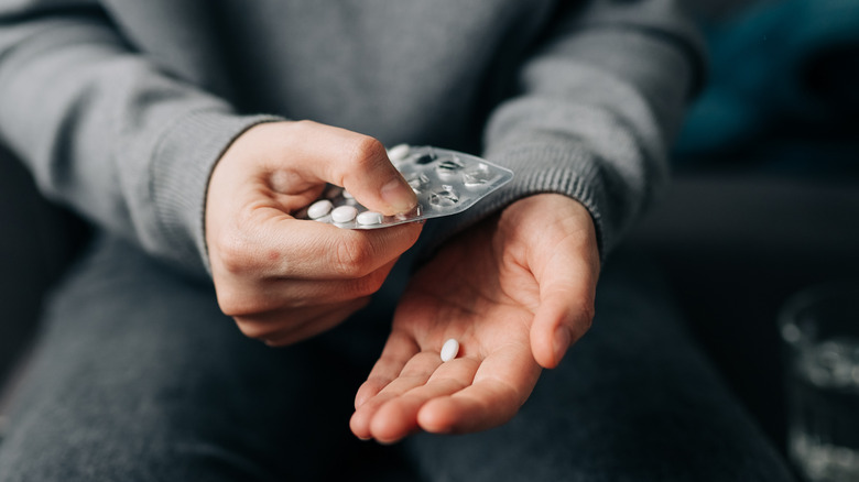 person taking antibiotics out of pill container