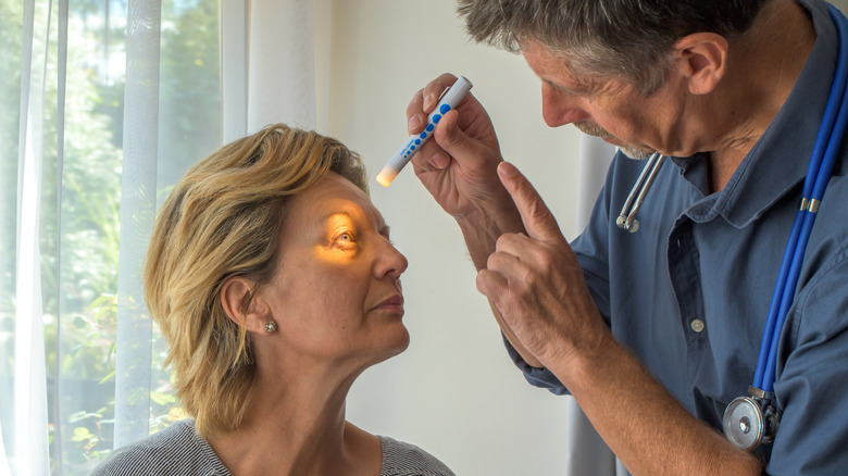 An eye doctor using a small light to see a woman's eye