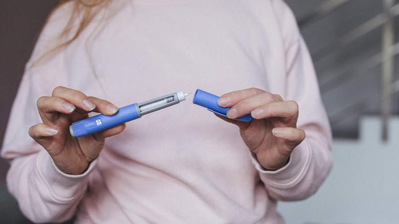 A woman's hands opening a GLP-1 agonist injection pen