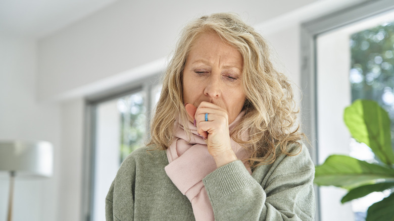 An older woman coughing into her hand