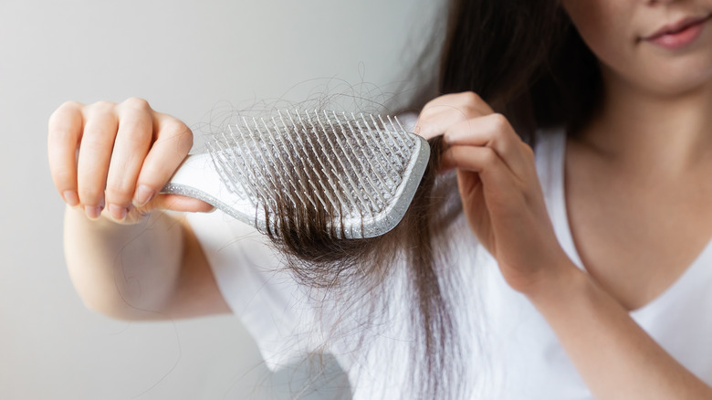 A woman pulls a hairbrush through long dark locks