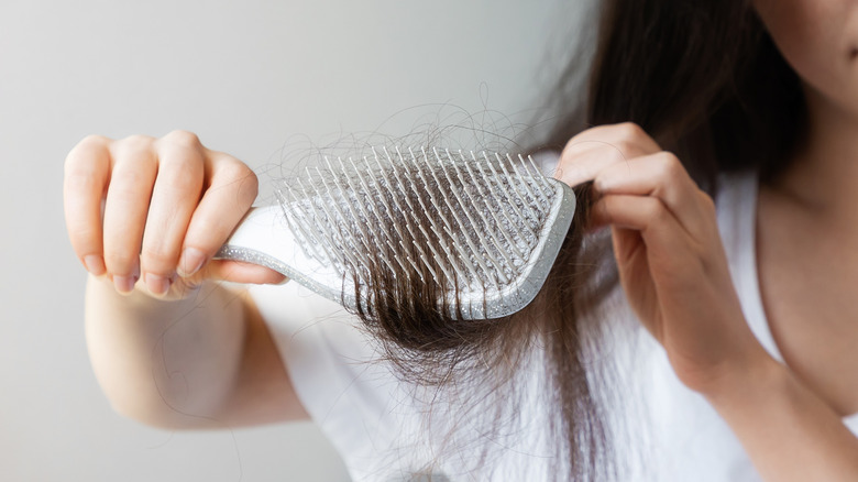 woman pulling hair brush through long dark tresses