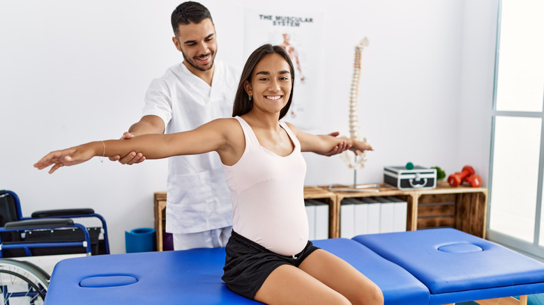 Physiotherapist helping a pregnant woman stretch