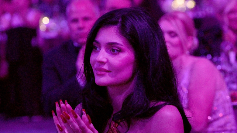 Kylie Jenner seated and applauding at an awards show