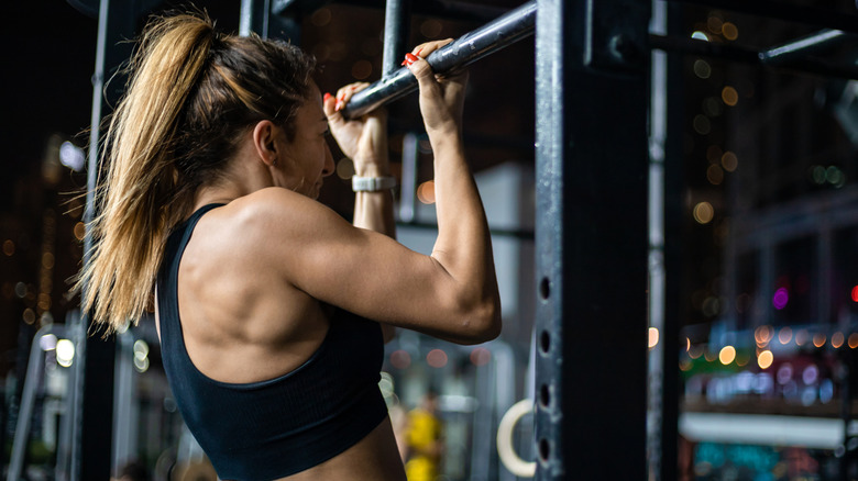 woman doing a pull-up at a gym