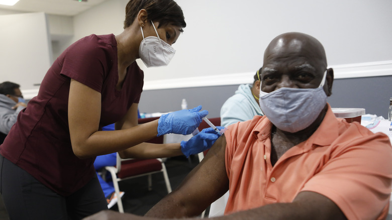 Man at COVID-19 vaccine drive receiving vaccine from nurse