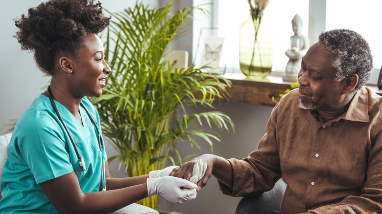 Nurse holding patient's hand and talking to him