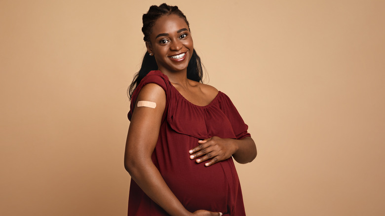 A pregnant woman of color smiling