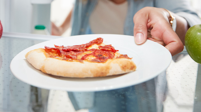 leftover pizza on refrigerator shelf