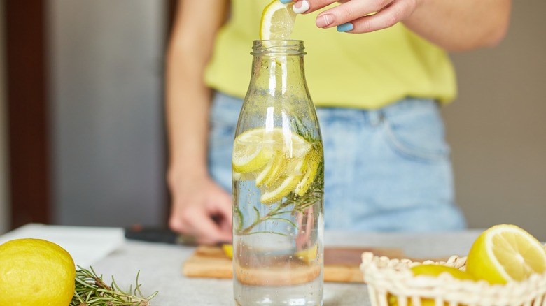 person putting slices of lemon in water 