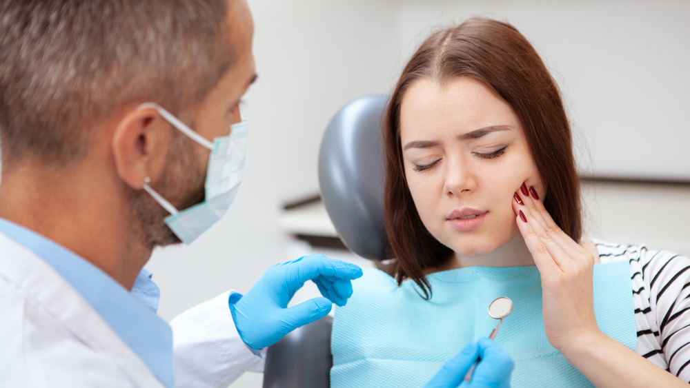 Woman experiencing a toothache in the dentist chair