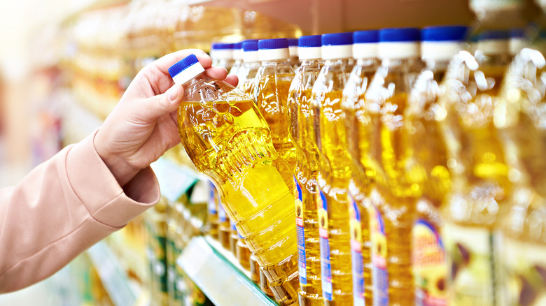 woman taking oil from a store shelf