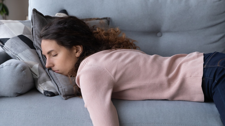 Woman sleeping on stomach on couch