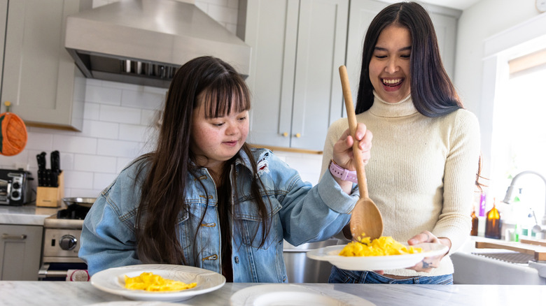 young girl and woman eating eggs in kitchen