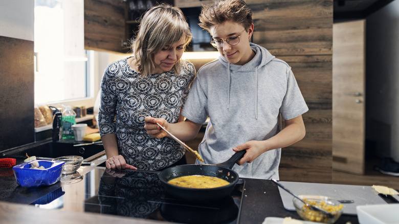 women and male teenager making scrambled eggs