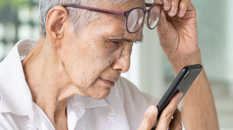 older woman having difficulty reading phone