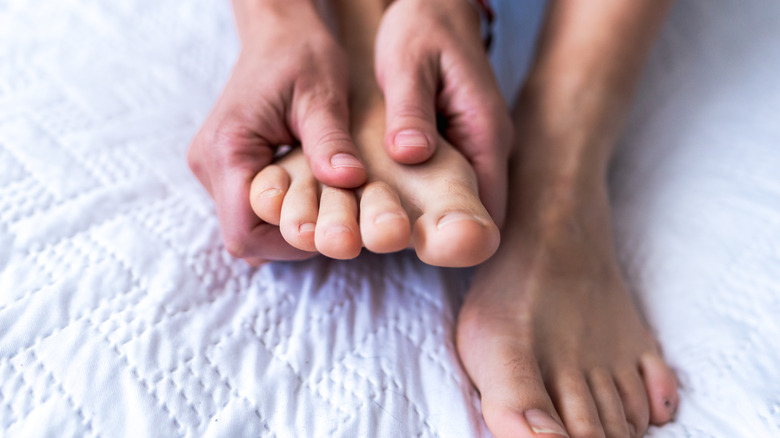woman massaging her feet in bed