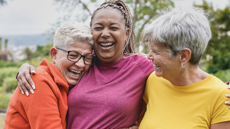 Three older woman hugging outdoors