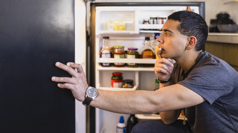 A man thinking while looking inside his refrigerator