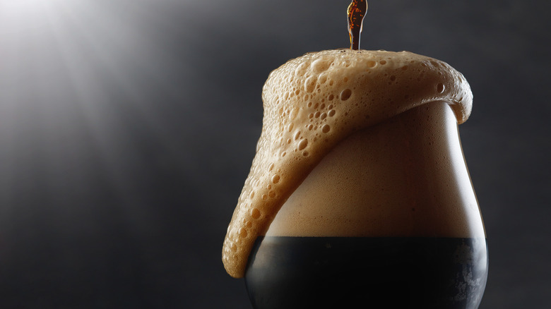 a dark beer overflowing