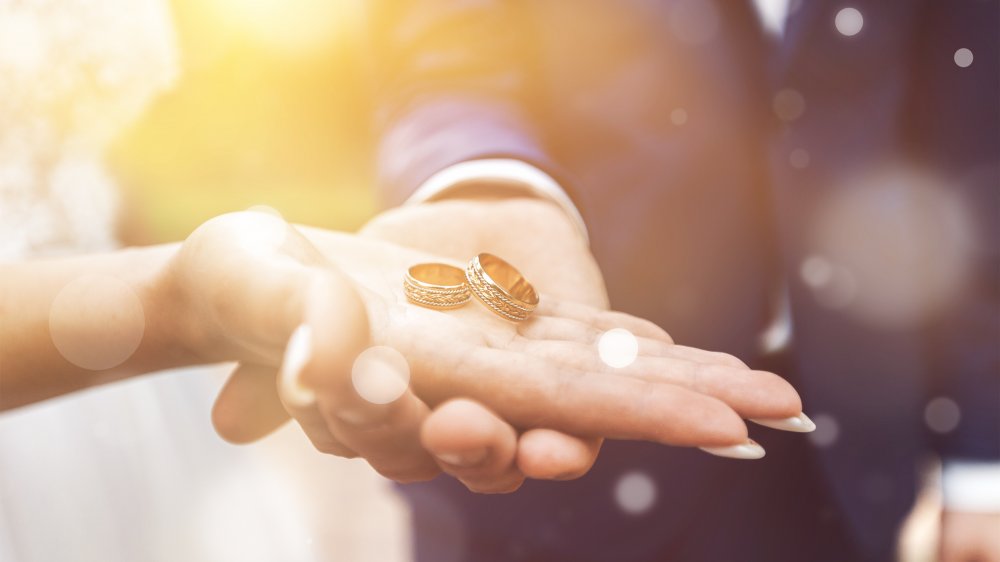 Two hands holding wedding rings