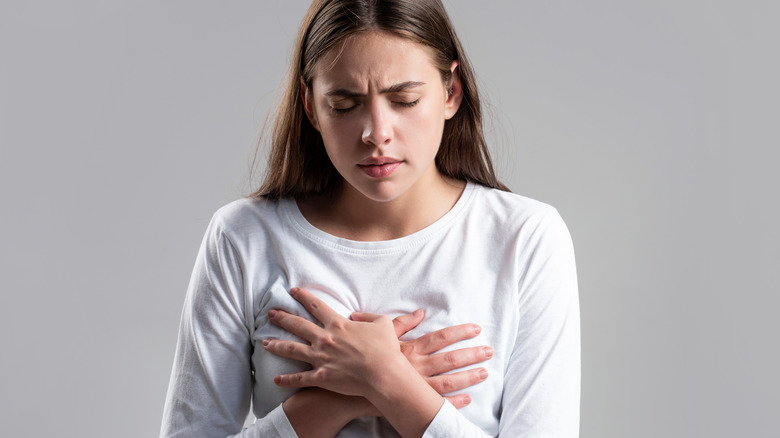 pained woman with hands over breasts