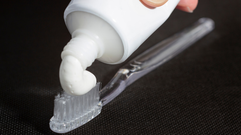 A hand squeezing toothpaste onto a toothbrush