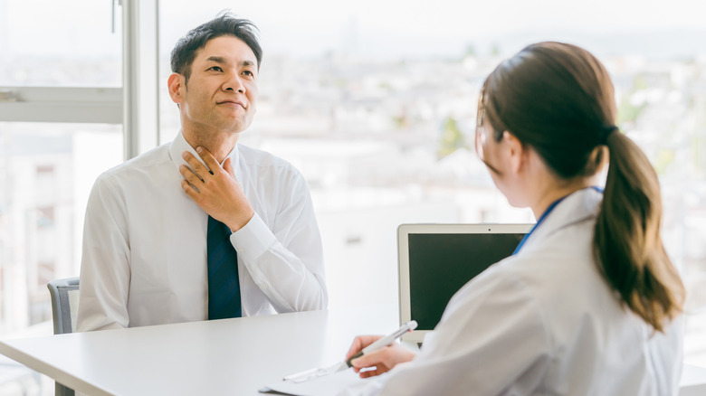 male patient holding throat while at doctor visit
