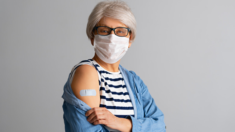 masked woman showing vaccine band-aid