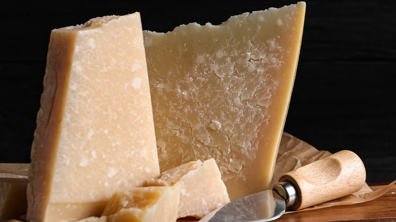 Parmesan cheese with board and knife on black wooden table