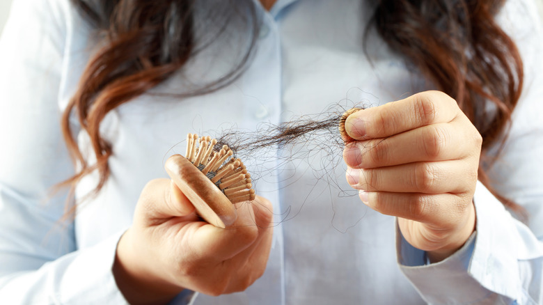 Woman pulling hair off of hairbrush