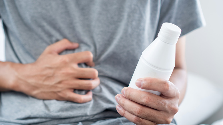 A man clutching a bottle of Antacid Gel in His Hand to Relief Acid Reflux, Heartburn, or Indigestion Symptoms