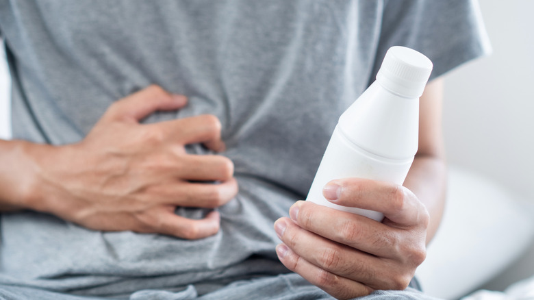 A man clutching a bottle of Antacid Gel in His Hand to Relief Acid Reflux, Heartburn, or Indigestion Symptoms
