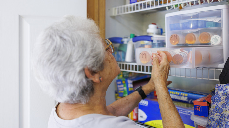 Senior woman rummaging through medicine cabinet