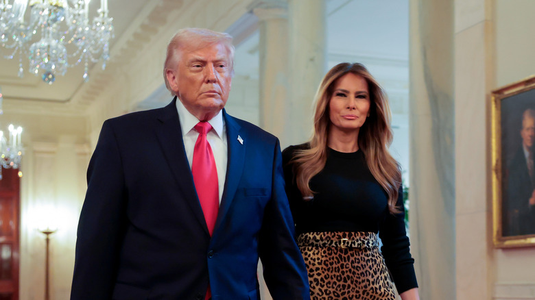 Melania Trump holds hands with husband Donald Trump while walking through the White House