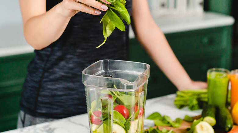 A woman adding leaves to a healthy shake