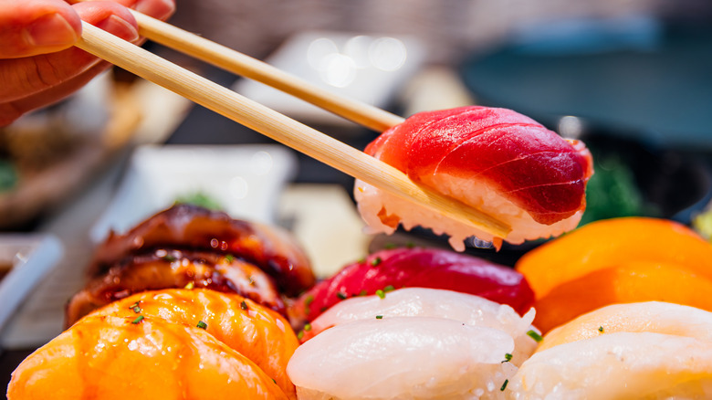 Person taking sushi using chopsticks