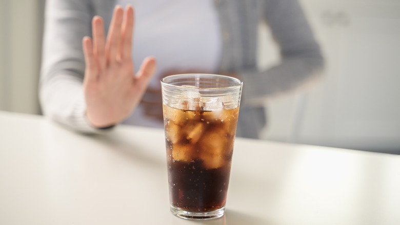 woman's hand pushing away soda glass