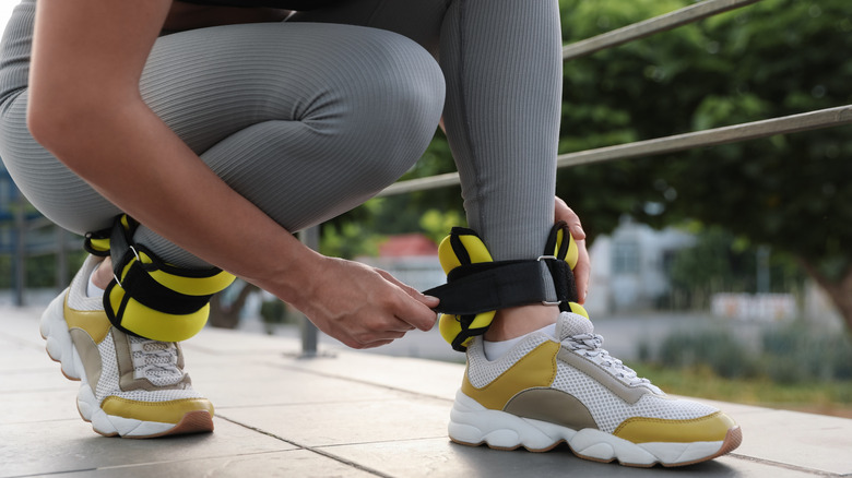 A woman putting on neoprene ankle weights outdoors