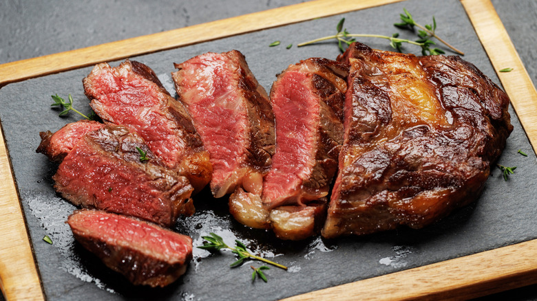 cooked ribeye steak on a wooden plank