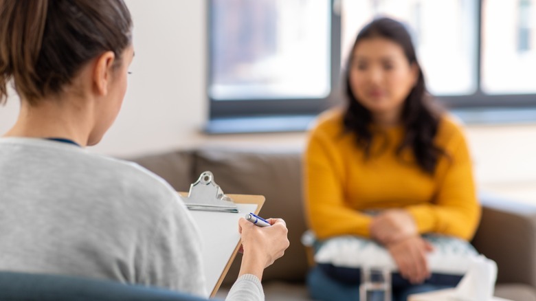 woman sitting with therapist with a clipboard