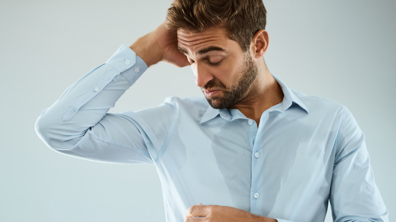 man noticing armpit odor and making face