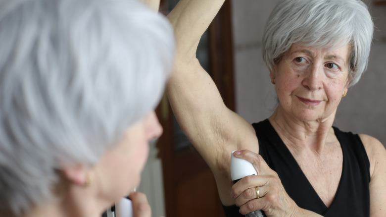 Senior woman applying deodorant in the bathroom
